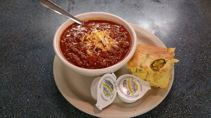Bowl of chili with cheese and a square of jalapeno cornbread