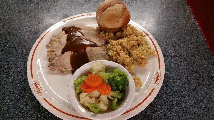 Roast dinner with gravy, dressing, a roll and steamed vegetables